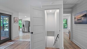 Un intérieur moderne avec un plancher en bois, une porte blanche donnant sur un couloir et un tableau accroché au mur.
