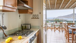 Una cocina con estufa, una mesa de madera y vista al mar.