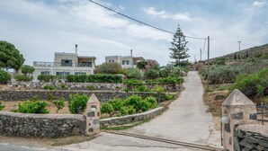 Un sendero rural que conduce a casas con muros de piedra y vegetación.