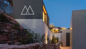 A modern building with a geometric logo, a stone wall, and a well-lit entrance.