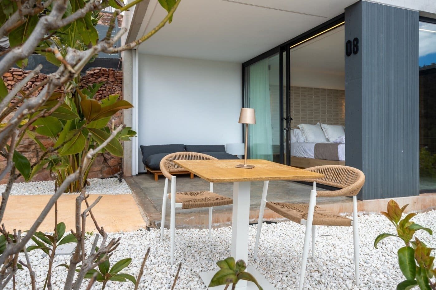 Un espacio exterior moderno con una mesa, dos sillas, un sofá y una lámpara.