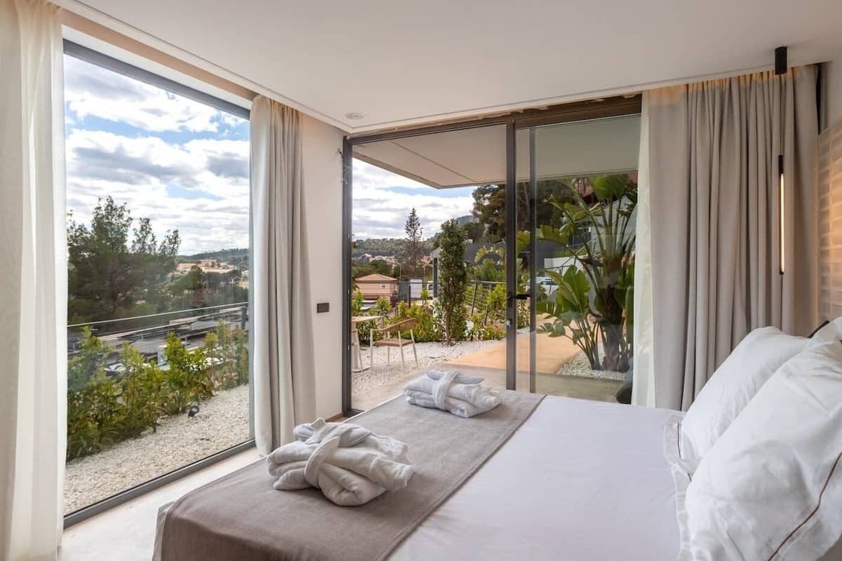 Un dormitorio con cama, vistas al exterior y una puerta corrediza de vidrio.
