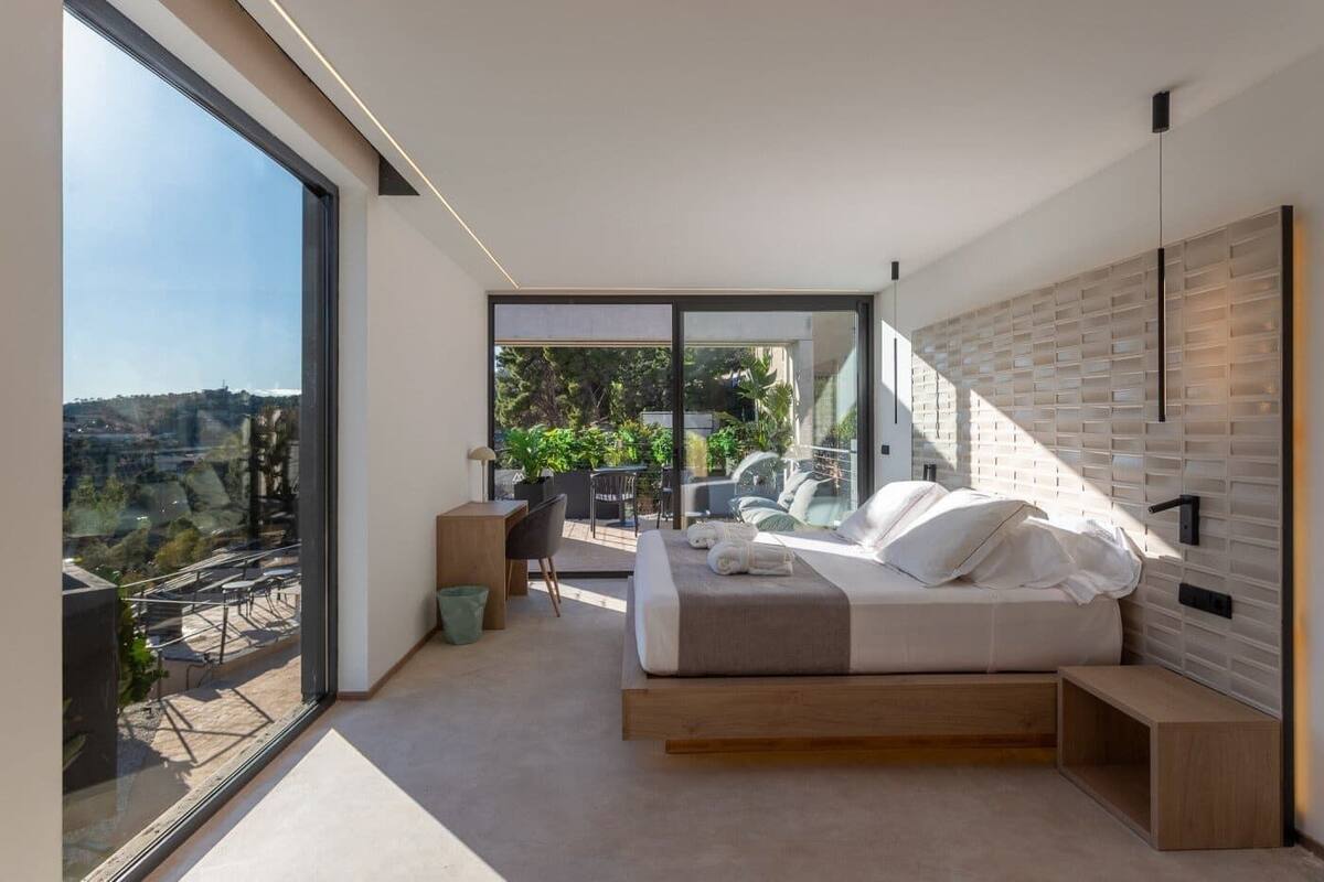 Un dormitorio moderno con una cama grande, un escritorio y vistas al exterior.