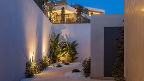 Een modern gebouw met een pad, wit grind en tropische planten.