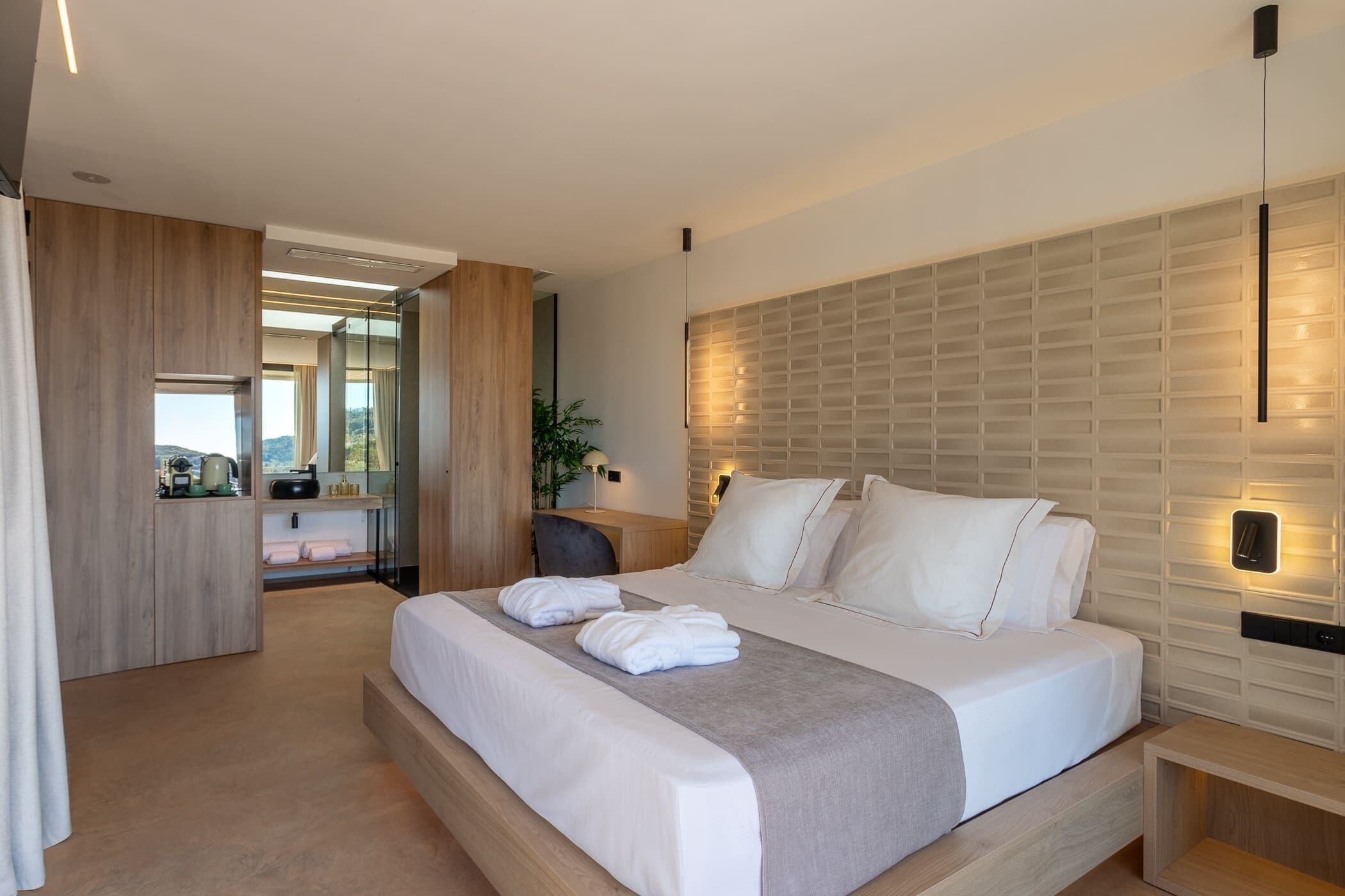 Una habitación de hotel moderna con una cama grande, un escritorio de madera y vistas al exterior.