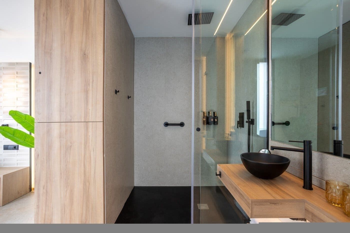 A modern bathroom with a glass shower enclosure, a wooden vanity, and a large mirror.