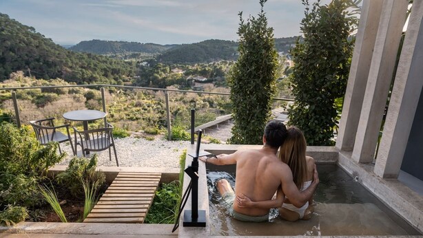 Een stel in een jacuzzi met uitzicht op een glooiend landschap.