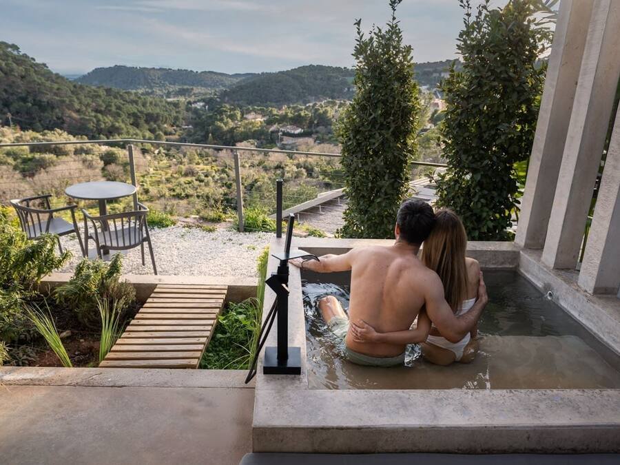Een stel in een jacuzzi met uitzicht op een glooiend landschap.