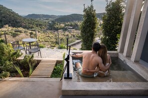 A couple in a hot tub with a view of a hilly landscape. - Hotel Boutique Serra Nature (Serra)