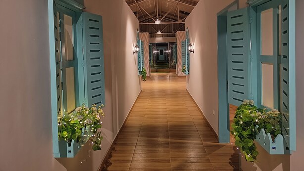 A corridor with wooden flooring, teal shutters, and wall-mounted lights. - FF21-Pods (Bengaluru)