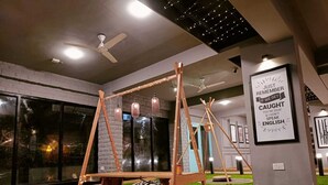 A modern interior with a swing set, green cushions, and a sign with a message. - FF21-Pods (Bengaluru)