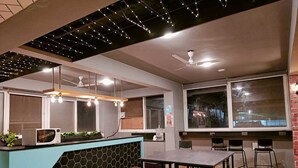A modern kitchen with a blue island, a hanging light fixture, and a ceiling fan. - FF21-Pods (Bengaluru)