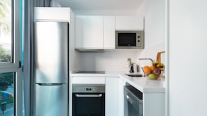A modern kitchen with stainless steel appliances, white cabinetry, and a fruit bowl on the counter.
