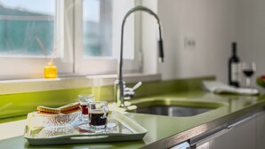 Un comptoir de cuisine avec un plateau de nourriture et de boissons, un robinet et une fenêtre où est posée une bougie.