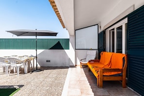 An outdoor patio with a table and chairs, a wooden sofa, a large umbrella, and a projector screen. - Villa 'D' Ana' with Private Pool, Private Garden and Wi-Fi (Sesimbra)