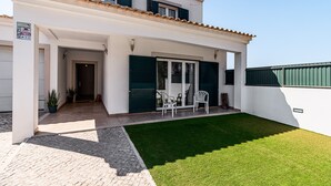 Une maison à deux étages dotée d’un patio couvert, d’une pelouse et d’une porte donnant sur l’intérieur.