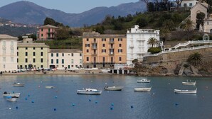 Une ville côtière avec des bâtiments le long du front de mer, des bateaux sur l’eau et des montagnes en arrière-plan.