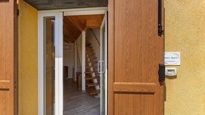 Une porte en bois avec une enseigne, un escalier et un mur jaune.