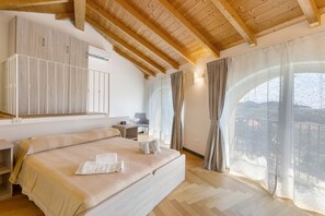 Un dormitorio con una cama grande, un escritorio, una silla y vistas al exterior a través de una ventana.