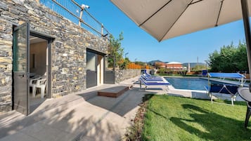 A stone building with a pool area, outdoor seating, and a covered patio.