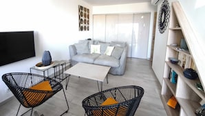 A modern living room with a grey sofa, two black wicker chairs, a white coffee table, and a flat-screen TV. - House with splendid view - Grosseto-Prugna (Grosseto-Prugna)