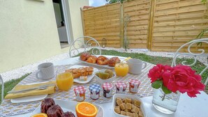 Una mesa de desayuno con croissants, zumo de naranja y diferentes mermeladas y untables.