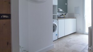 Un lavadero con lavadora, secadora y un pequeño estante con utensilios de cocina.