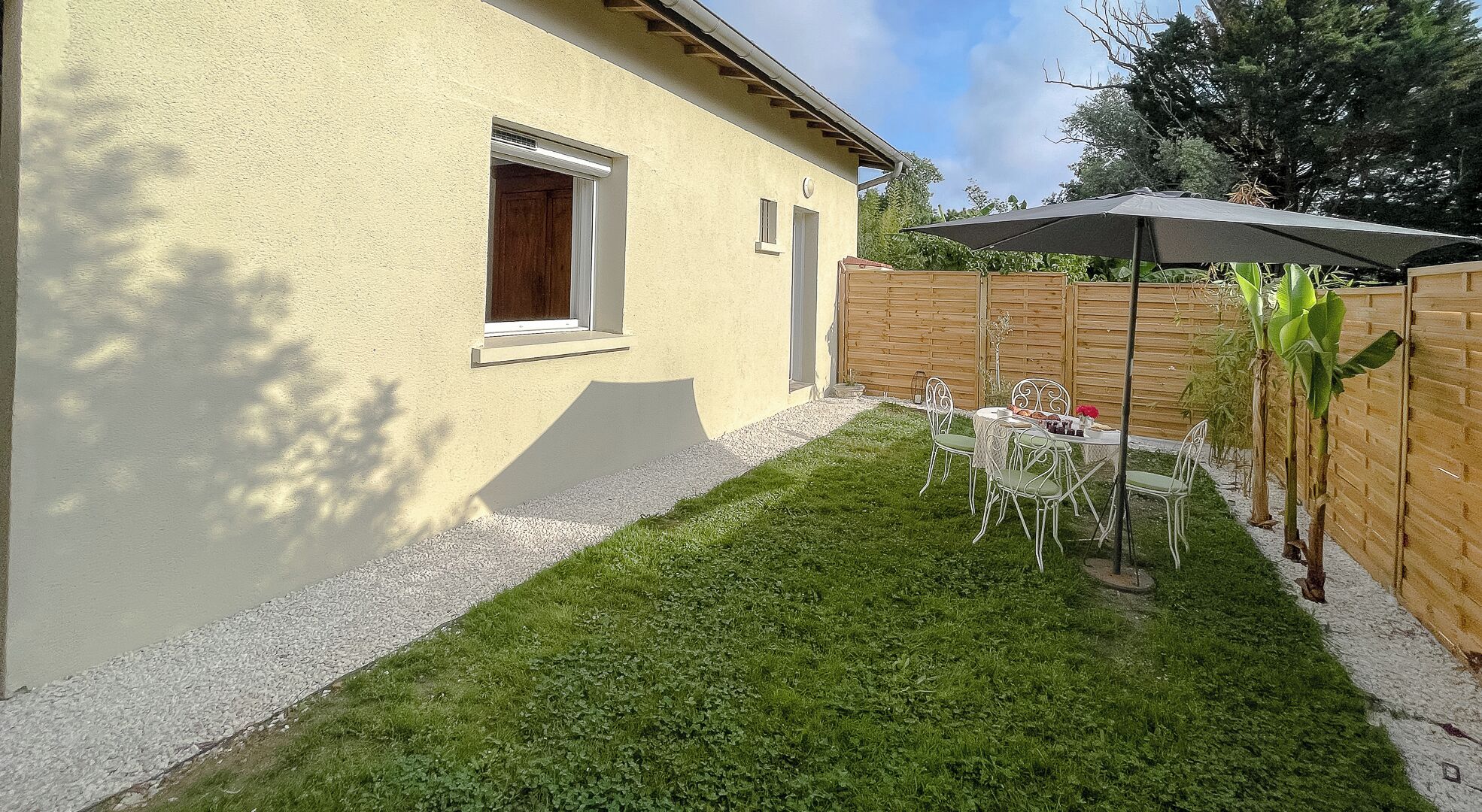 A backyard with a patio table and chairs, a wooden fence, and a small garden area.