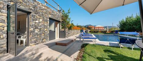 A stone building with a pool area, outdoor seating, and a covered patio.
