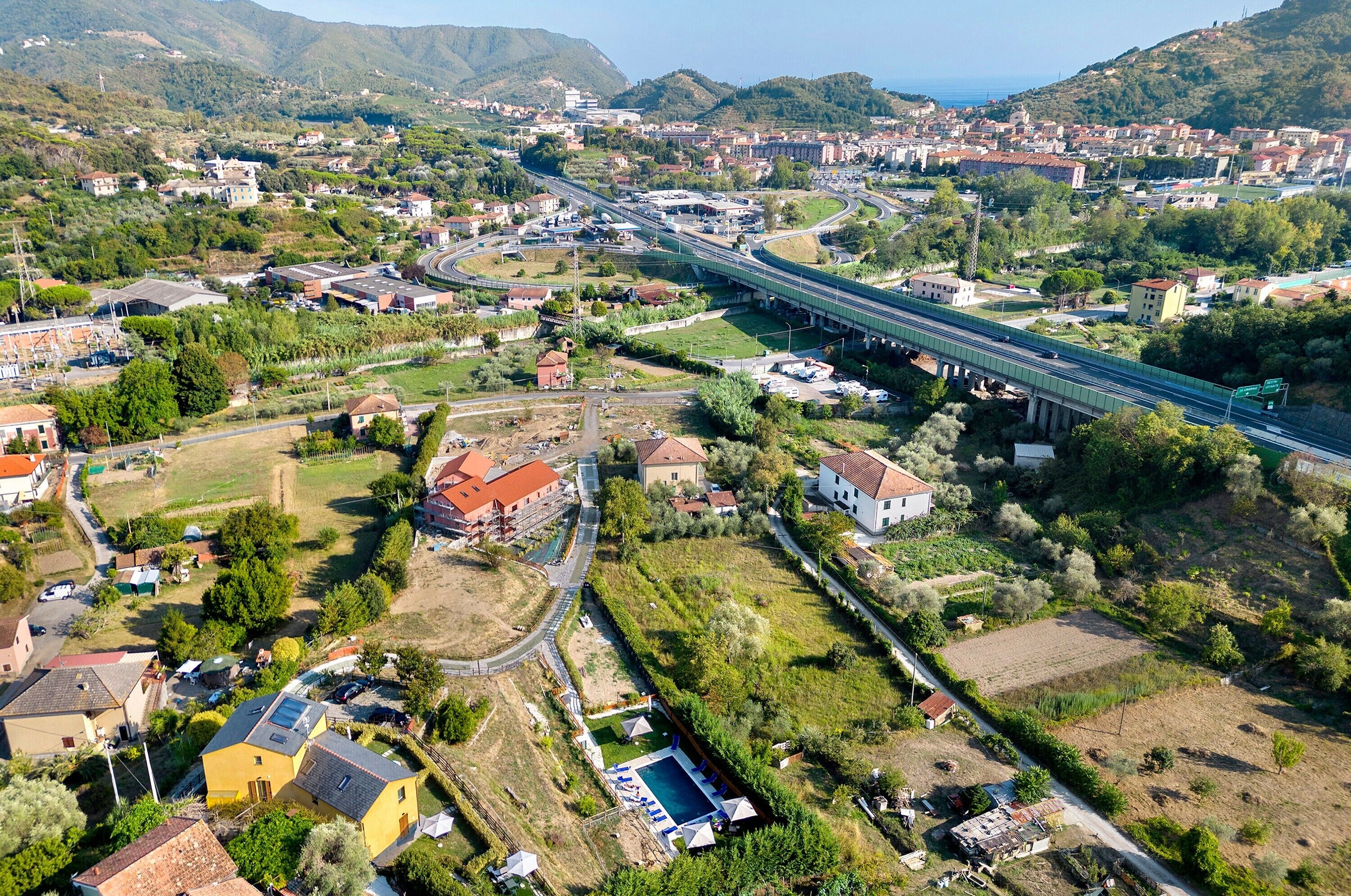 An aerial view of a coastal town with a prominent bridge, residential areas, and a large swimming pool.