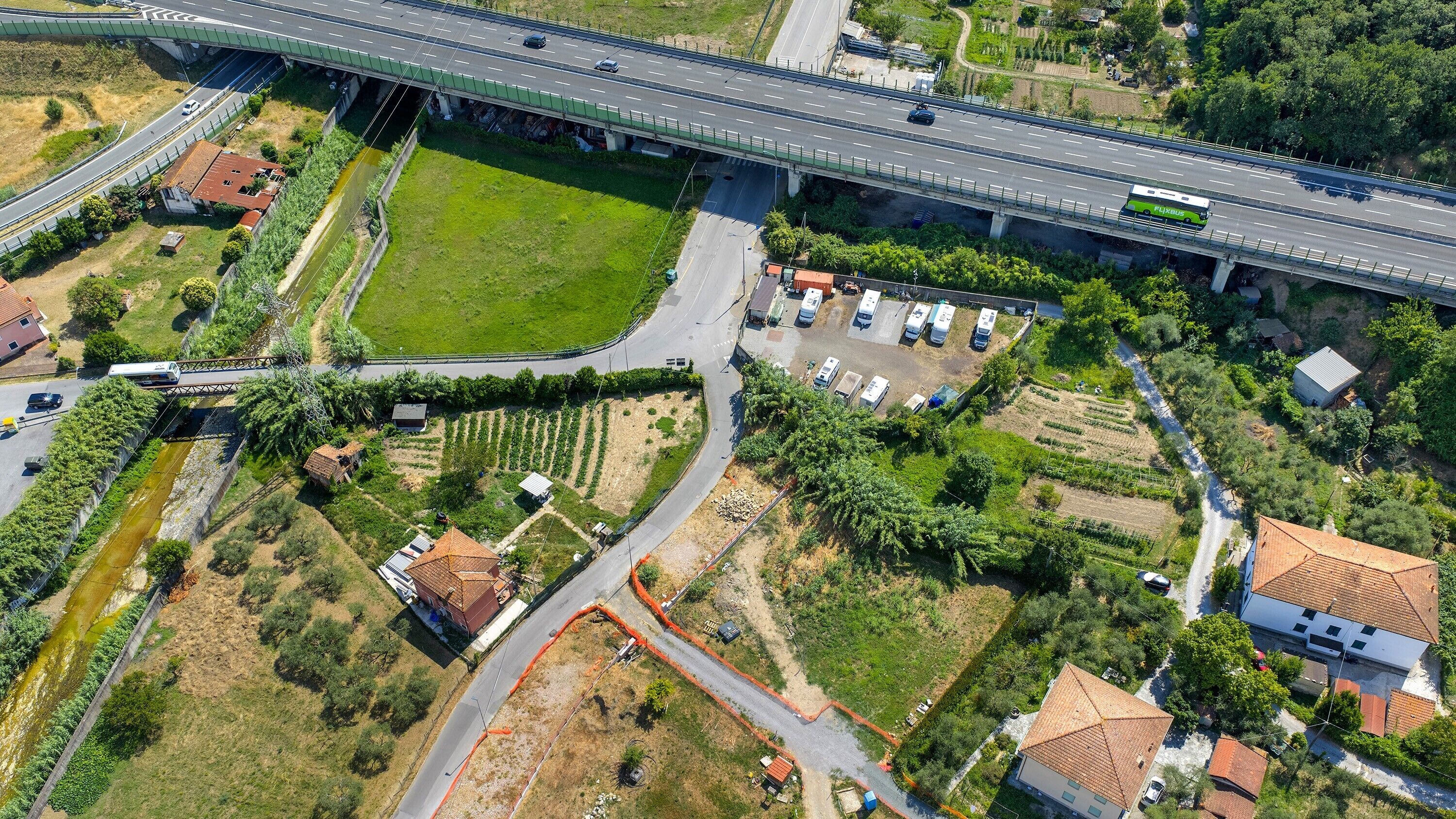 Vue aérienne d’une autoroute avec un pont, des champs verdoyants et des zones résidentielles.