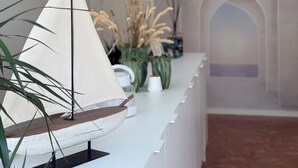 Un intérieur moderne avec une maquette de voilier posée sur un comptoir blanc, une porte et un couloir doté d’un plafond en arc de cercle.