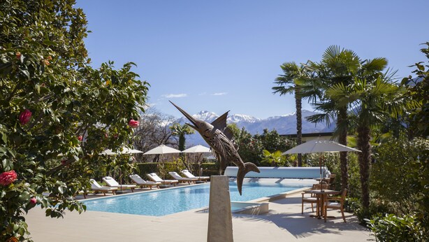 Une piscine avec des chaises longues, une statue et une vue sur la montagne.