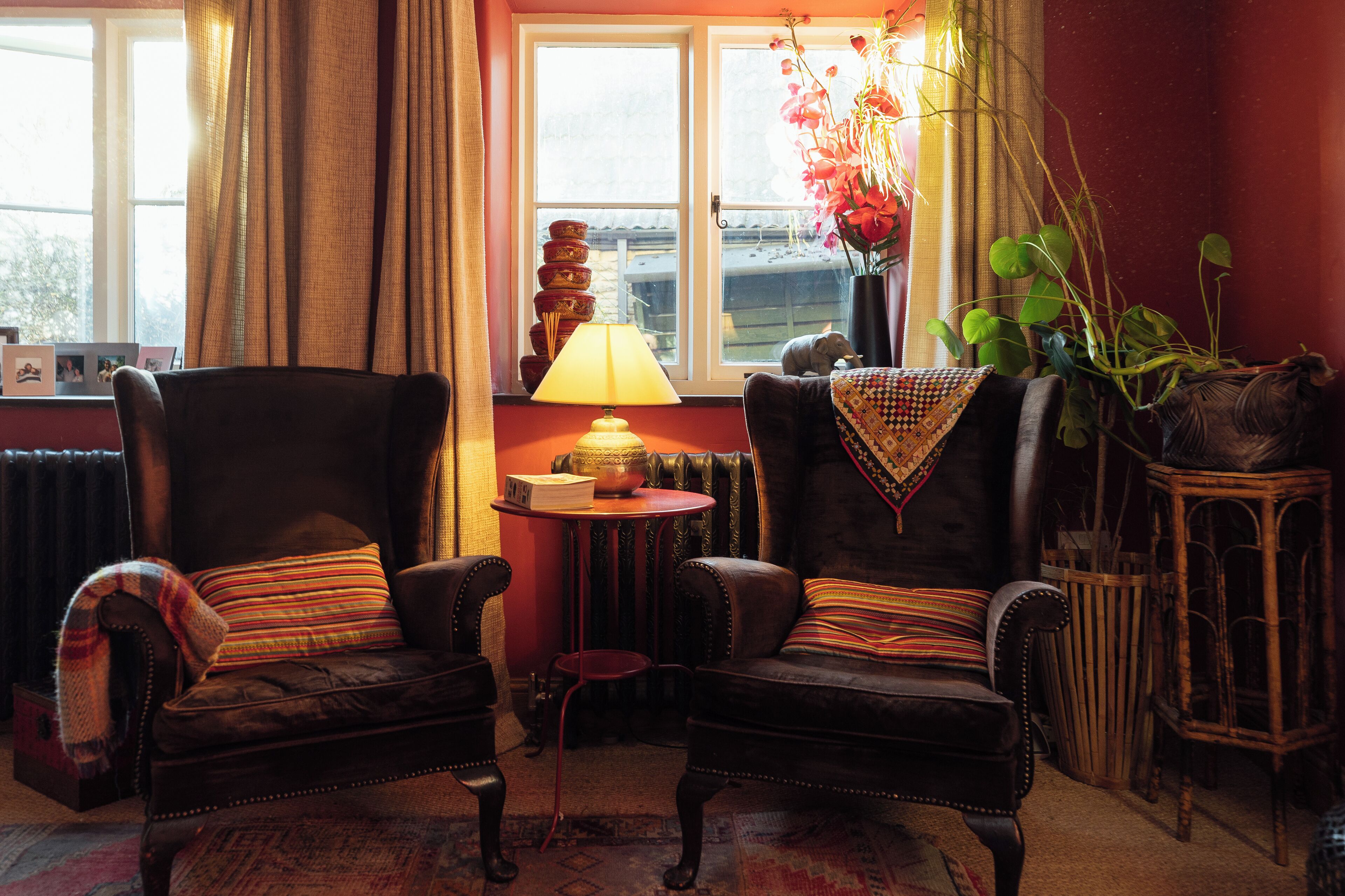 A cozy room with two leather armchairs, a small table with a lamp, and a window with curtains.