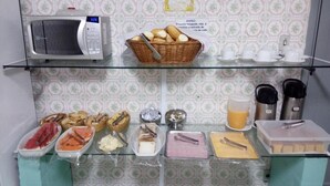 Montaje de un bufé de desayuno con diversos alimentos, un microondas y equipo para preparar café.