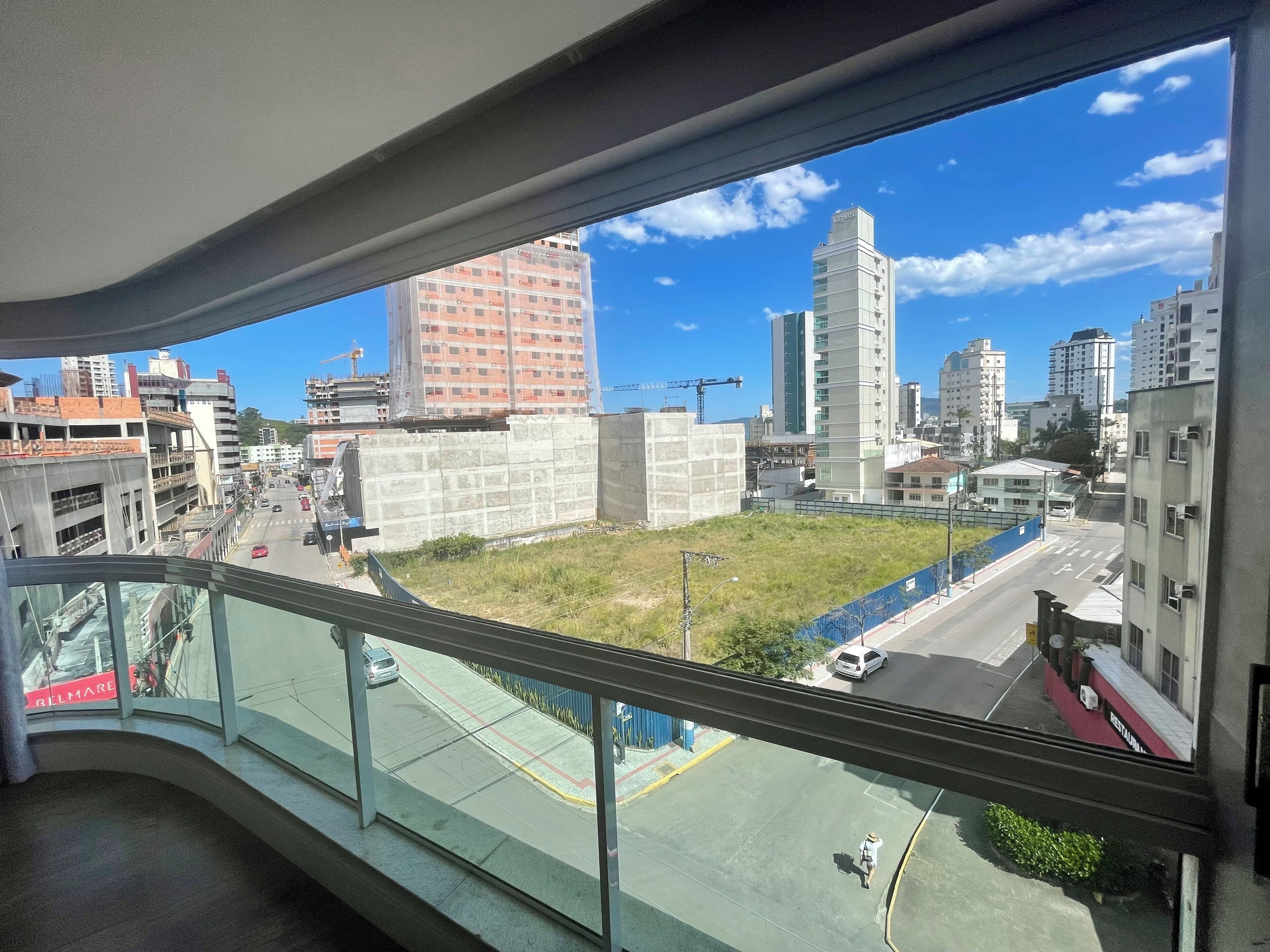 Une vue depuis un balcon donnant sur un paysage urbain, avec des immeubles, une route et un chantier de construction.