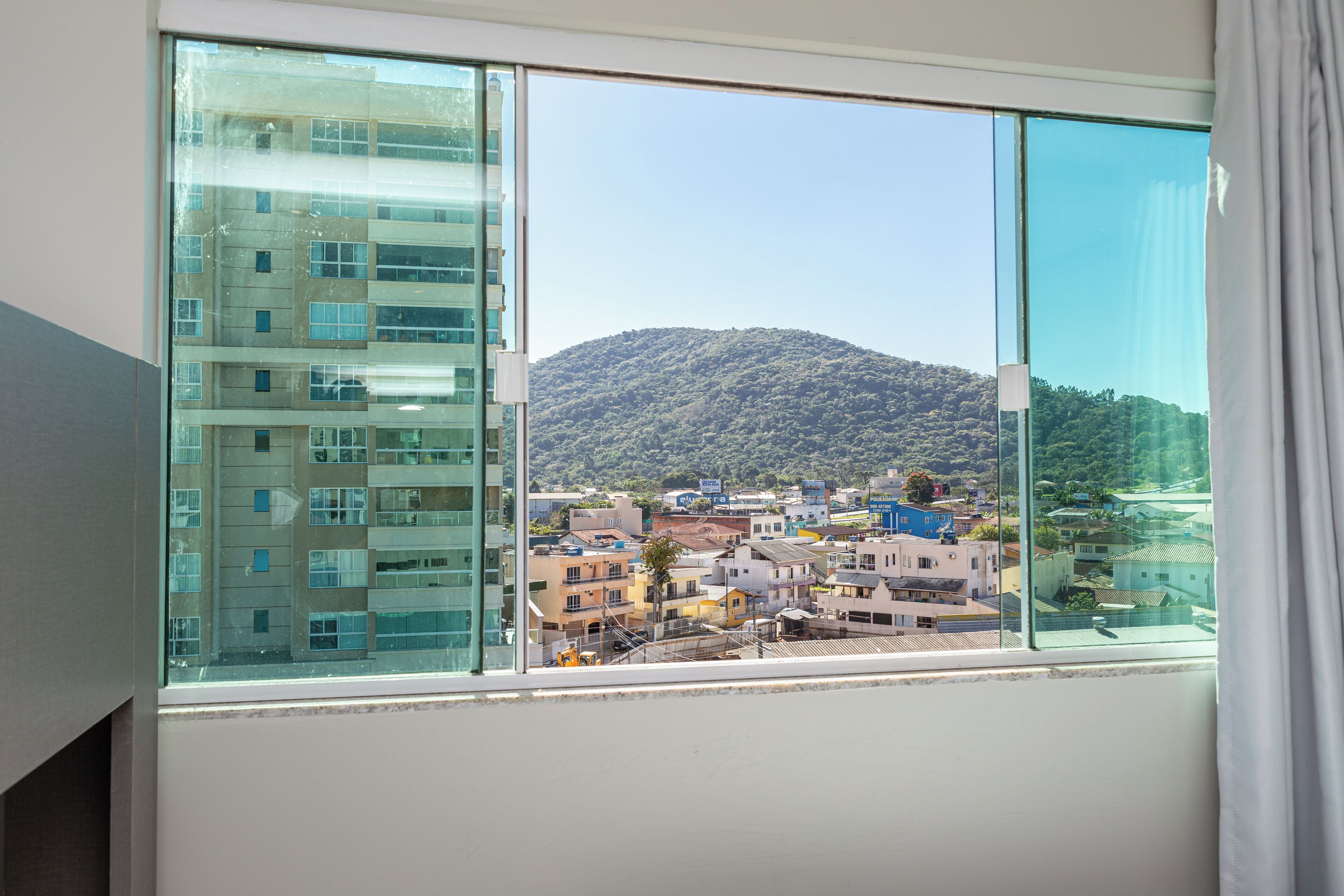 A view from a window overlooking a town with a mountain in the distance.