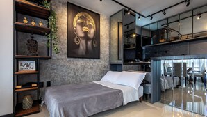 A modern bedroom with a bed, a large framed artwork, a shelf with decorative items, and a staircase leading to an upper level. - Nilmare Apart Hotel (Itapema)