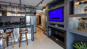 A modern kitchen with a large TV, bar stools, and a fireplace. - Nilmare Apart Hotel (Itapema)