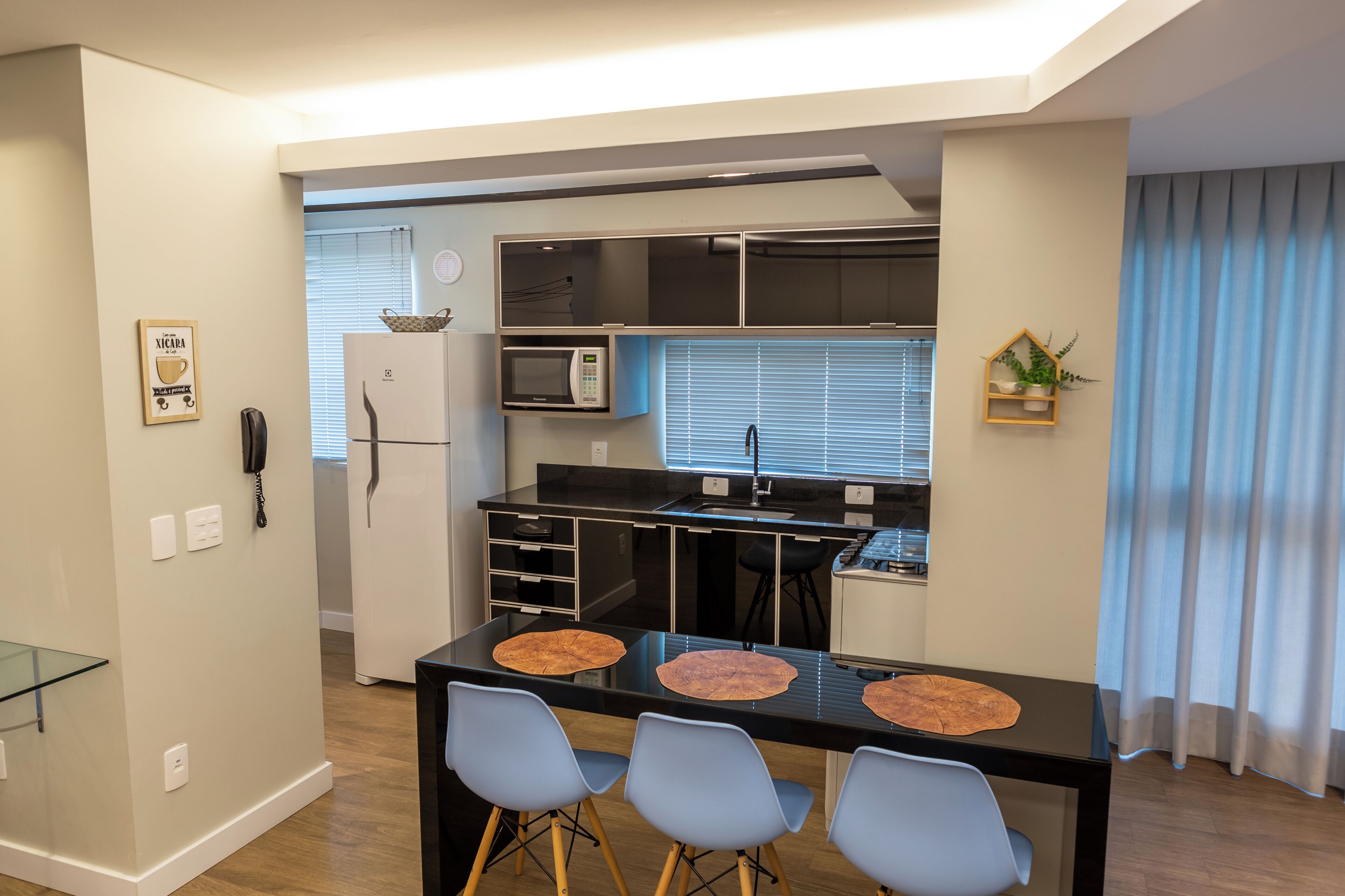 Una cocina compacta con microondas, refrigerador y comedor con mesa y sillas.