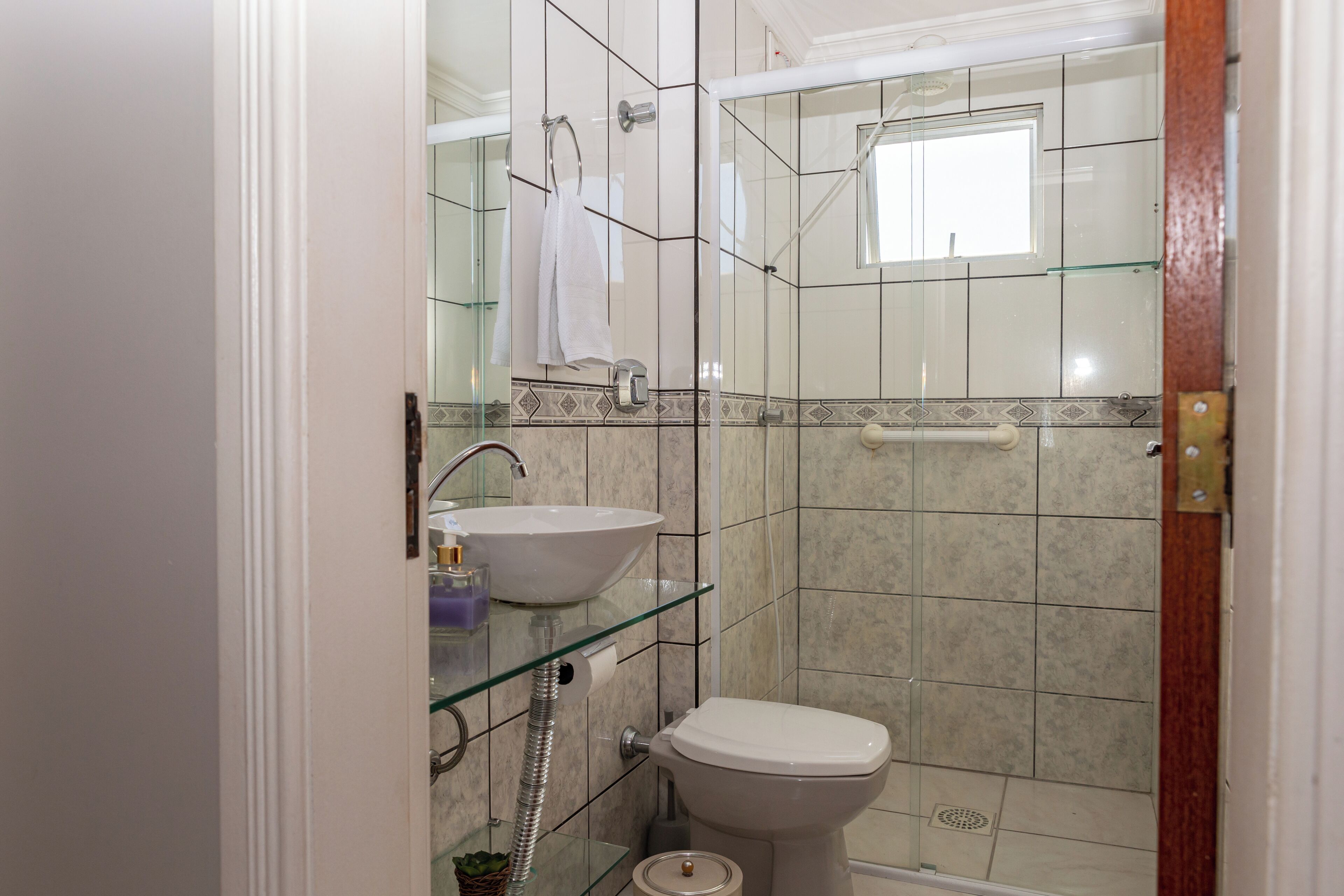 Een badkamer met een douchecabine van glas, een wit wastafelmeubel en een toilet.