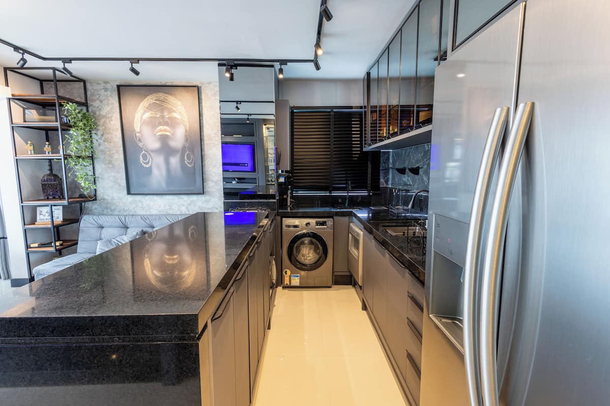 A modern kitchen with a built-in washer and dryer, stainless steel appliances, and a marble countertop.
