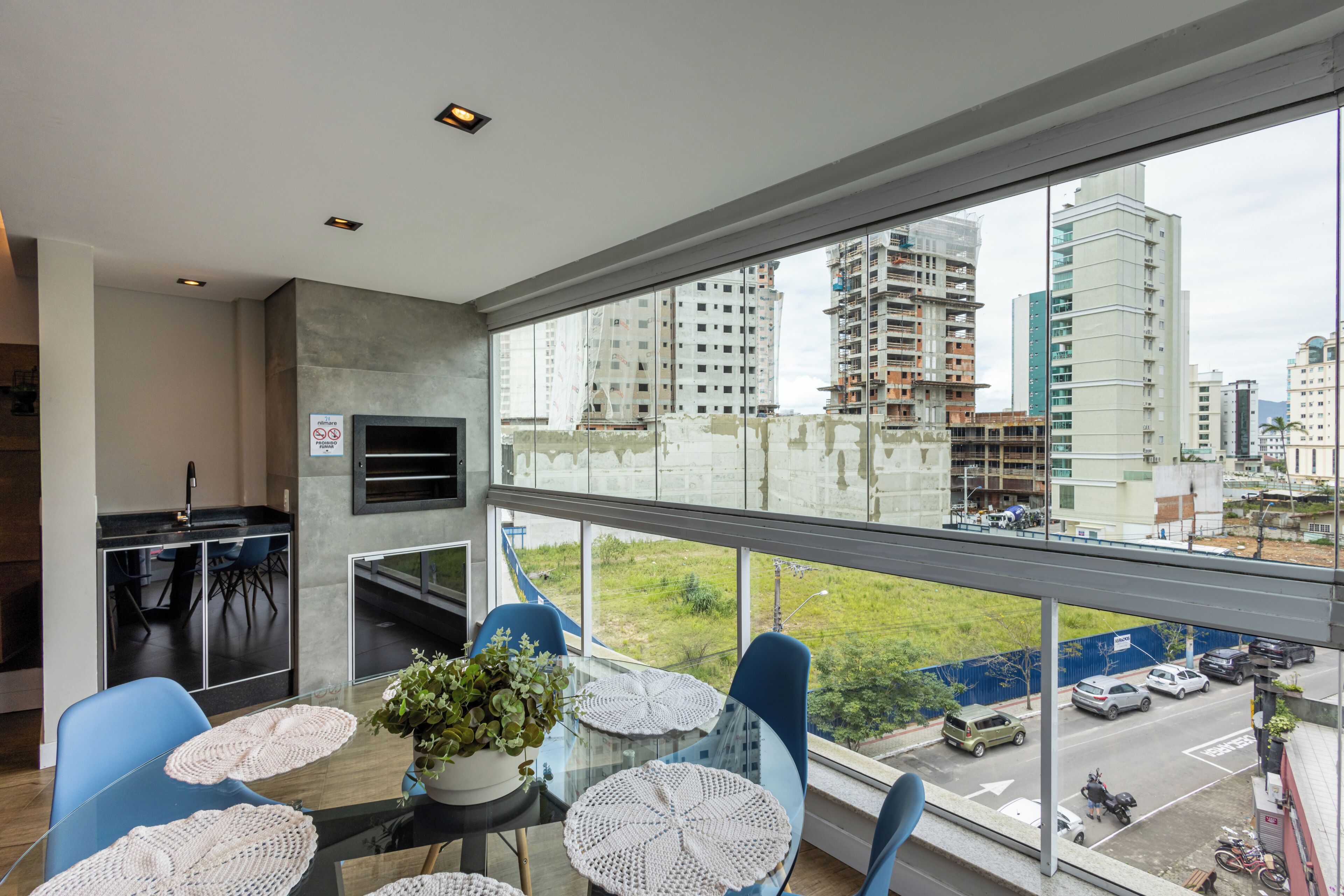 Ein modernes Zimmer mit Küchenbereich, einem Esstisch mit Stühlen und einem großen Fenster mit Blick auf die Stadt.
