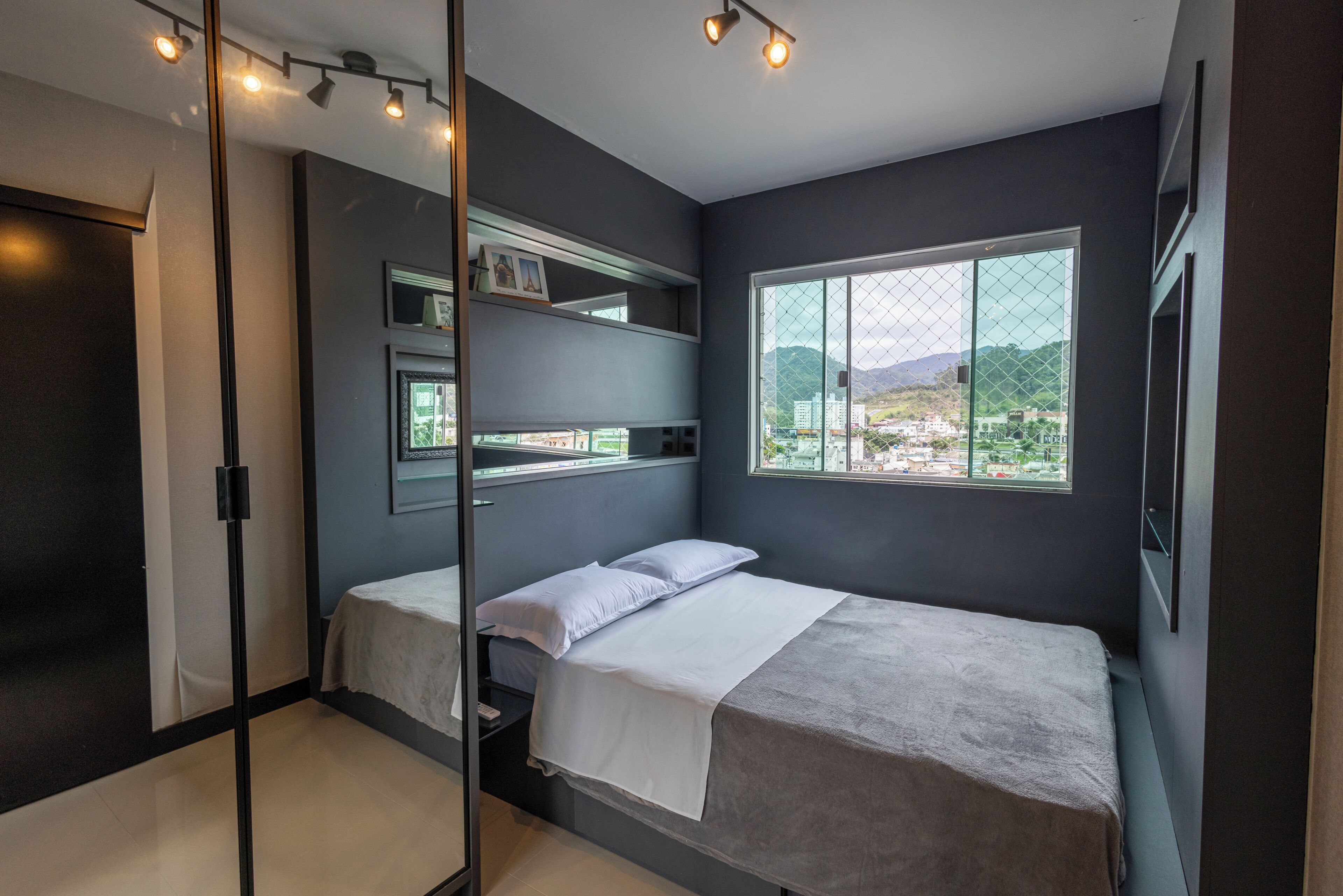 A modern bedroom with a bunk bed, a large window with a view, and a glass partition.