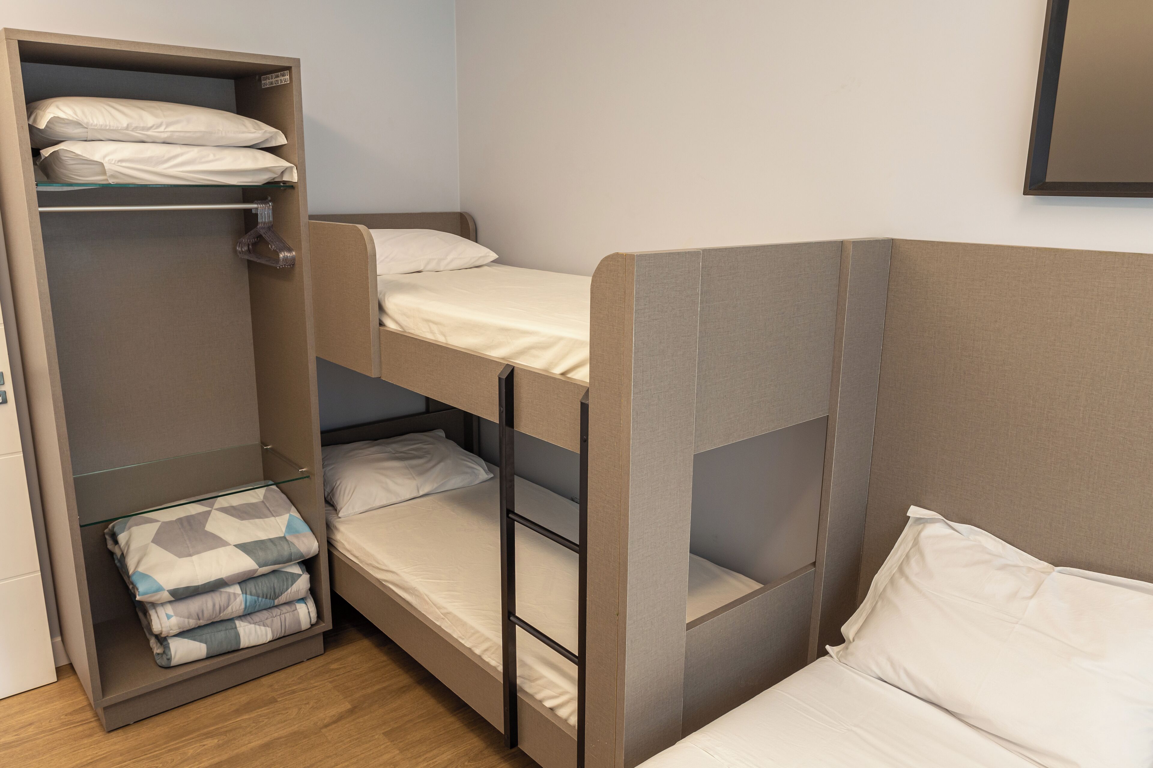 A bunk bed with a lower bunk and a separate bed, a wardrobe, and a mirror on the wall.