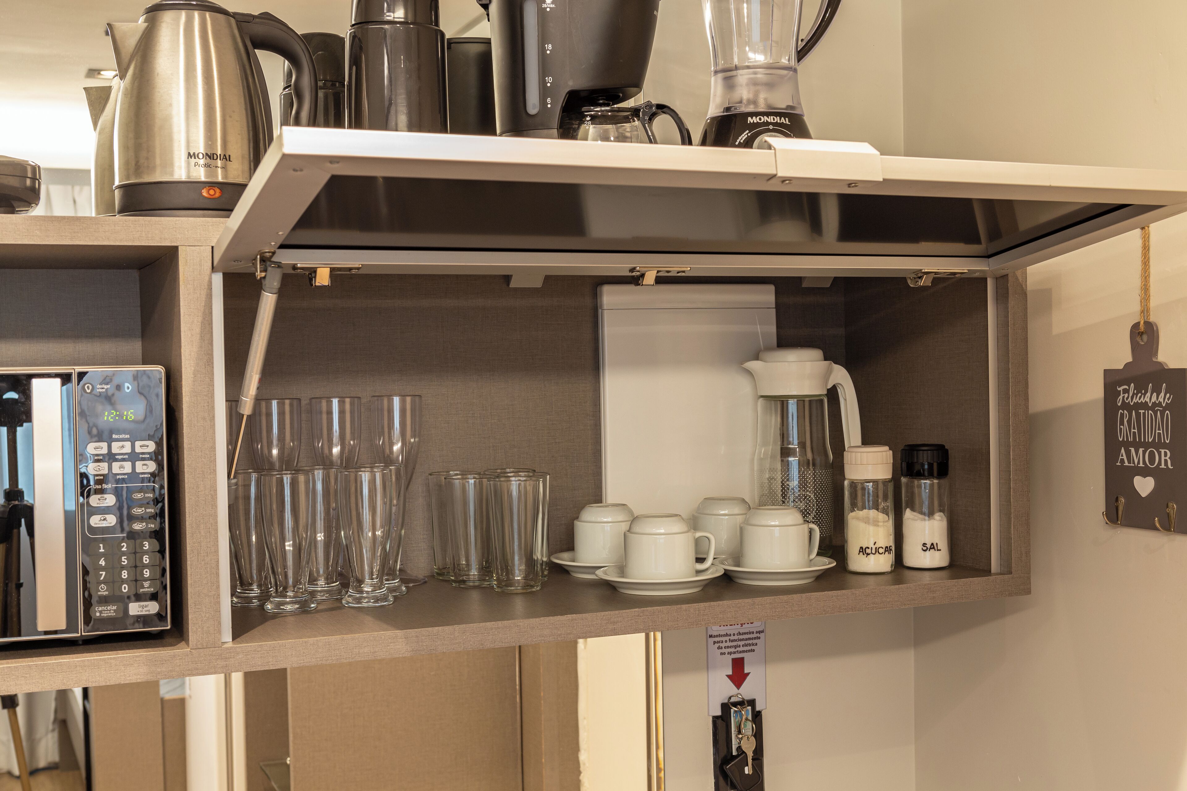 A kitchen with a coffee maker, kettle, blender, and various glassware.