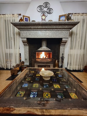 A fireplace with a fire, a decorative bowl in front, and a patterned floor. - Large Holiday Home 'El Rozado' for 22 Guests with Garden in Sierra de Gredos (Piedralaves)