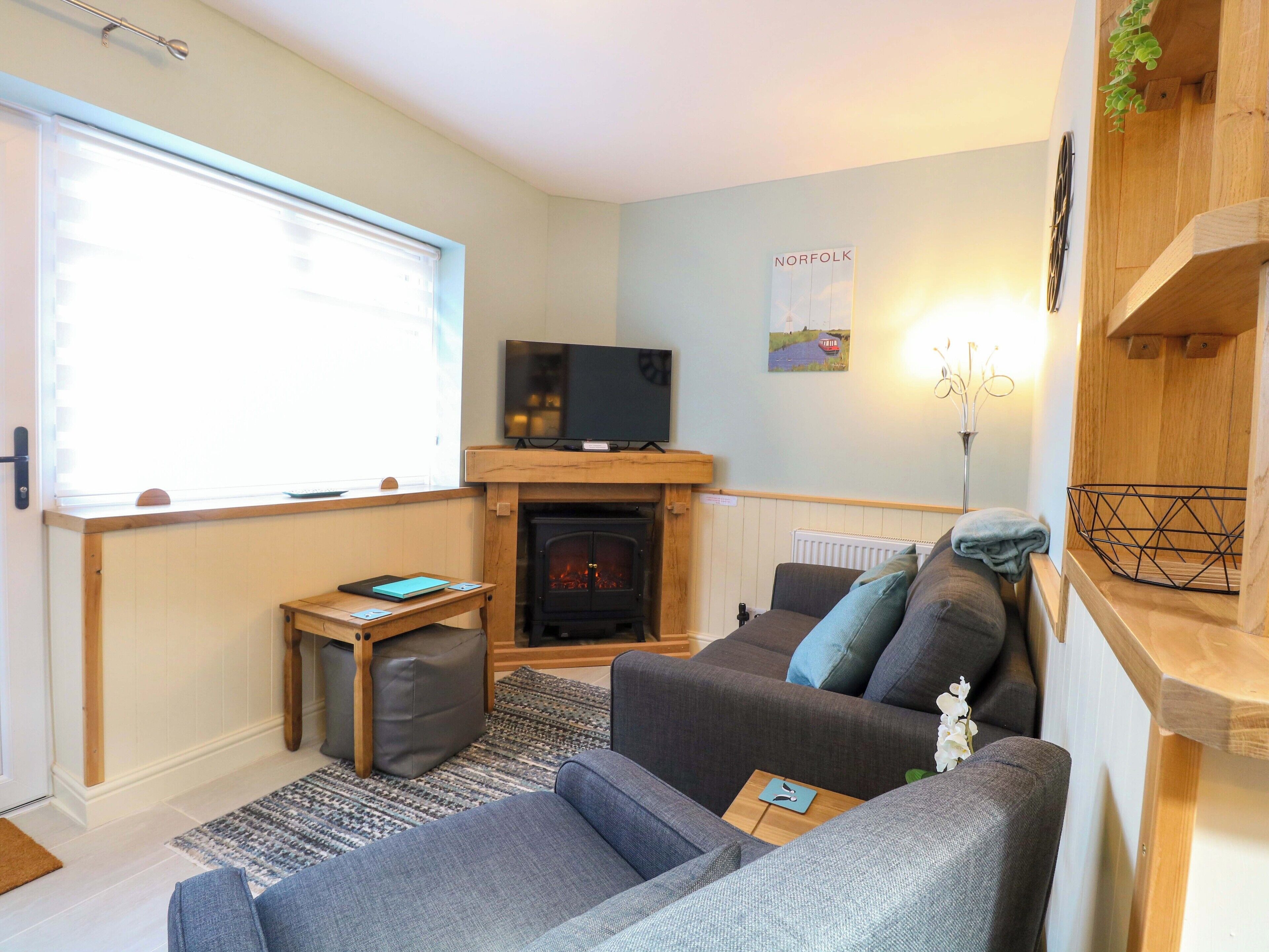 A cozy living room with a sofa, a small table, a fireplace, and a television.