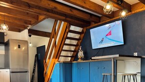 Una cocina moderna con refrigerador empotrado, armarios azules y techo de madera.