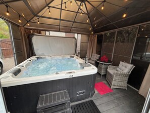 A hot tub with a canopy, surrounded by wicker furniture and a red rug. - 3 Bed-sleeps 6-hot Tub-pet Friendly-parking (Coventry)